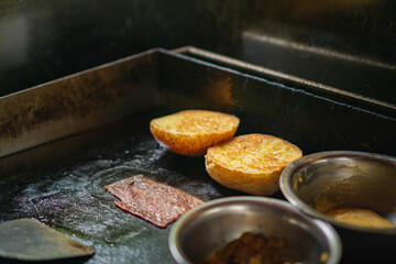 toasted hamburger bun on a griddle with the other burger condiment