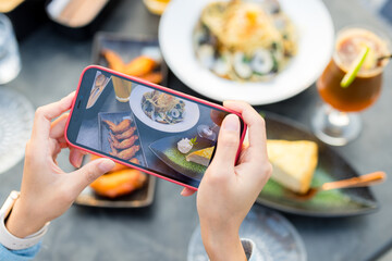 Woman cellphone to take photo on the food in restaurant