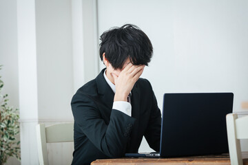 パソコンの前で頭を抱える男性　Business