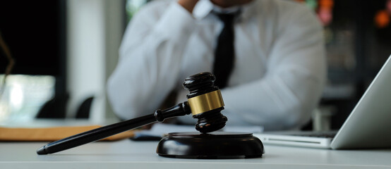 Judge gavel with Justice lawyers having team meeting at law firm in background. Concepts of law.