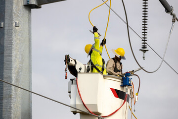 Linemen At Work Installing High Voltage Cables To Insulators