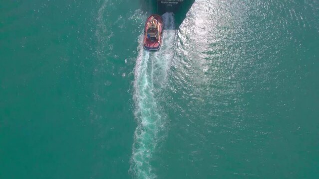 LNG gas tanker underway, accompanied by a small tug boat. Top down tilting shot