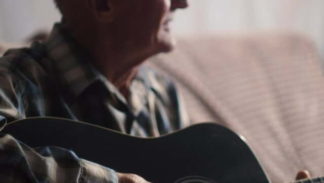 Portrait of an elderly gentlemen playing acoustic guitar, melancholy nostalgia on old man's face, retirement hobby concept.