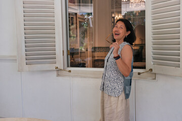 A housewife standing outside her large house window in the morning