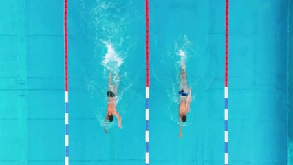 Drone flies with 2 swimmers who swim lengths next to each other