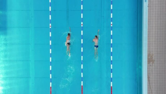 Top down drone shot of 2 swimmers swimming along a swimming pool