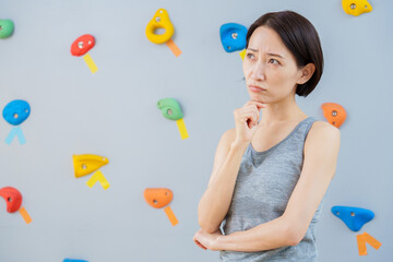 ボルダリングジムで考え事をする女性