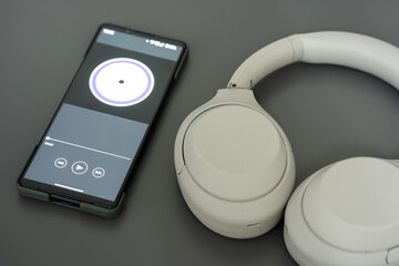 Music player on screen of mobile phone and wireless headphone. Selective focus. isolated on gray background.