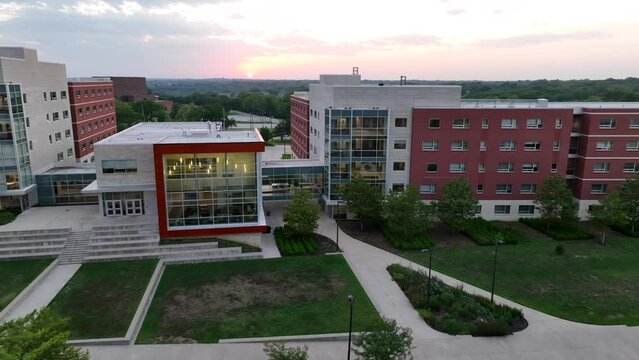 Modern college dormitories in university campus in USA. Aerial establishing shot of student housing at dusk during sunset.