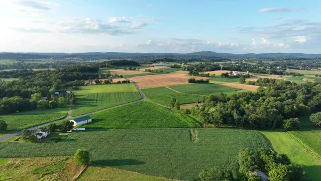 Rolling hills of rural USA. Aerial truck shot of American farmland in summer. Beautiful golden hour sunset over agricultural fields.