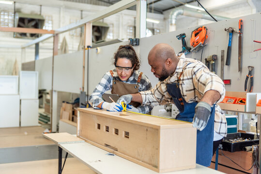 Two colleague young aged carpenter standing aim equipment tool for wood furniture at wood plank in workshop. coworker carpenter working craft with wood diy tool in workbench shop carpentry