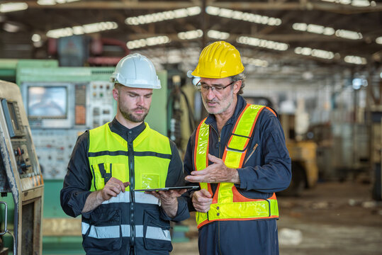 Two professional engineer worker technician assistant in helmet inspection check old machine construction factory with colleague manager. check old machinery production construction operating