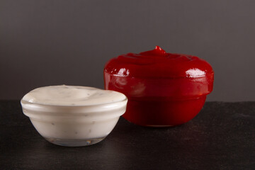Red and white dipping sauces on black slate serving board with blank space. Vibrant culinary...