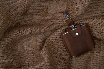 Hip flask in saddle leather case  on sack cloth background. Banner with copy space for text place - obrazy, fototapety, plakaty