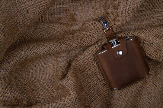 Hip flask in saddle leather case  on sack cloth background. Banner with copy space for text place