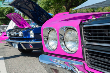 Vintage pink muscle car on display at automotive show.