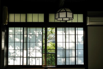 Dappled light falling across the paper screen windows of a traditional ryokan (guesthouse) on a sunny morning in Sengokuhara, Hakone - Kanagawa, Japan