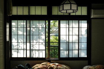 Dappled light falling across the paper screen windows of a traditional ryokan (guesthouse) on a...
