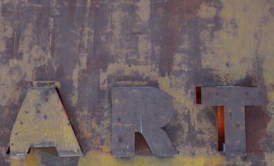 Embossed letters form the word art on rusty surface