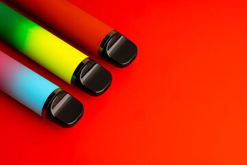 Disposable electronic cigarettes on red background close up