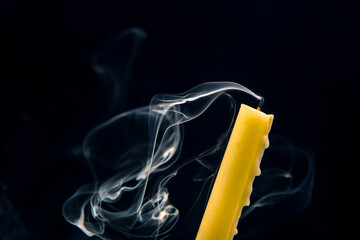 Smoke from an extinguished candle on a dark background. The concept of spirituality and the end of...