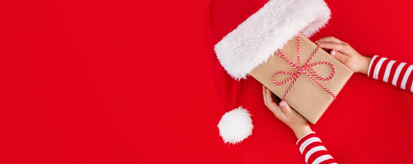 gift box in children's hands on a red background, presenting a gift, christmas background