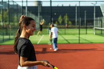 Two girls with badminton rackets on the football field.