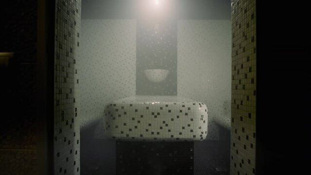 A Turkish steam sauna � hammam is seen without people inside. There is a table in the center of the room. Some amount of steam fills the hammam.