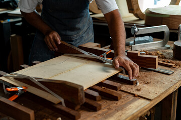 Guitar luthier ties rope, drives wedge to join spruce boards