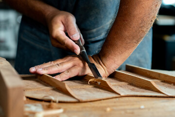 Close-up of guitar luthier using chisel to shave bracing of acoustic guitar. - obrazy, fototapety, plakaty