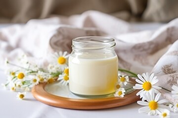 Obraz na płótnie Canvas chamomile tea in a glass pot by a cream throw on a bed