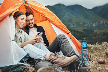 Couple, tent and camping with phone, smile and reading for holiday, web blog and morning in countryside. Man, woman and relax with vacation, social media and adventure with love, outdoor and freedom - obrazy, fototapety, plakaty