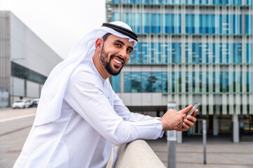 Arab middle-eastern man wearing emirati kandora traditional clothing in the city - Arabian muslim businessman strolling in urban business centre.