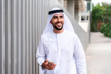 Fotobehang Abu Dhabi Arab middle-eastern man wearing emirati kandora traditional clothing in the city - Arabian muslim businessman strolling in urban business centre.
