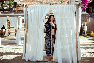 A girl in a black robe is standing in a beach tent