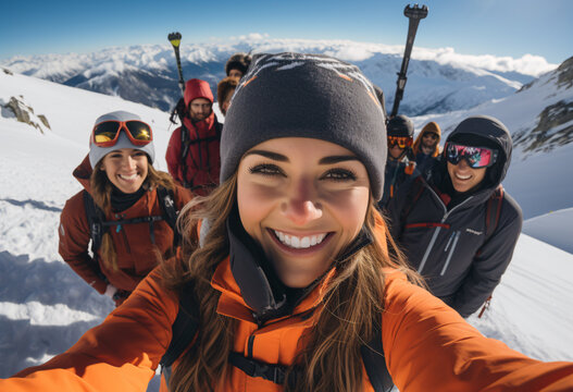 A lifestyle group photo of young women and men with ski goggles wearing winter clothing and helmet taking selfie with good friends in the alps, content and happy