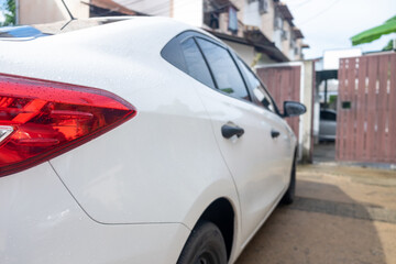 Rear side of a white car parking in front of a house door