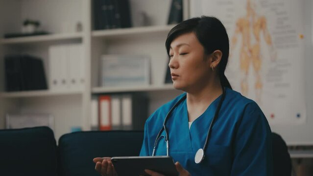 Asian woman rehabilitation physician consulting a patient, typing on tablet