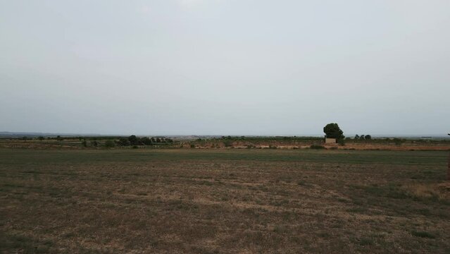 Aerial dolly right over field, passing by traditional tool shed, Tarrega, Spain