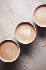 Three cups of cafe latte on a sleek and minimalist grey marble table.
