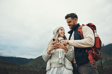 Couple, phone and travel or hiking in nature with information, social media chat or map for outdoor journey. Happy people below in backpack and mountains trekking with mobile or search for location