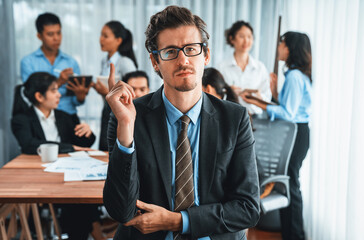 Portrait of happy businessman looking at camera, making finger pointing gesture for advertising product with motion blur background of business people movement in dynamic business meeting. Habiliment - obrazy, fototapety, plakaty