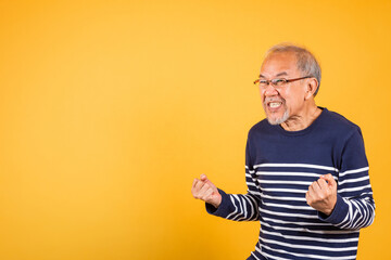 Happy Asian elder man with glasses excited say yes gesture like winner studio shot isolated on...