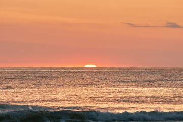 The glowing sun sinking on the horizon of the sea or ocean