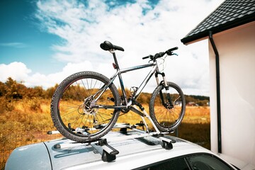 Fototapeta premium Bicycles on Car Roof Under the Open Sky. Transportation and logistics of large loads and travel by car. Summer vacation activities.