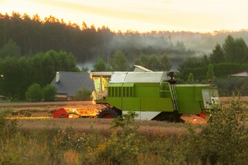 Agricultural machinery. Tractor Cultivating Fields at Sunset. Combine harvester at work....