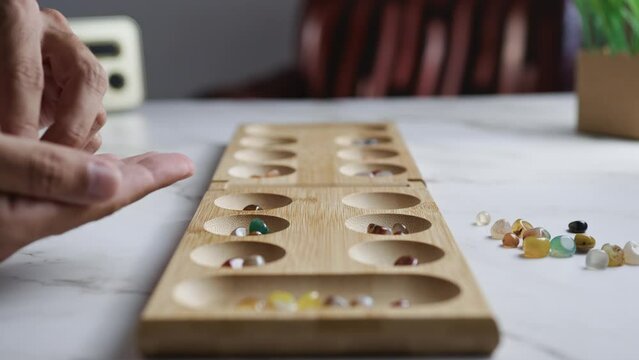 Playing traditional strategic board game called mancala
