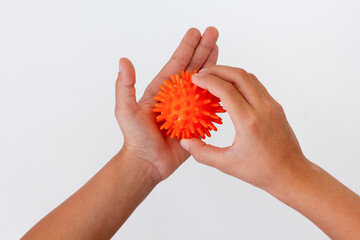 Top view of cropped child hands doing exercise using spiky ball over white background