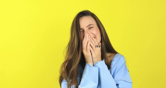 Happy joyful young woman wear blue sweater laughing out loud after hearing ridiculous anecdote, funny joke, feeling carefree amused, positive lifestyle, cover her mouth isolated on yellow background.