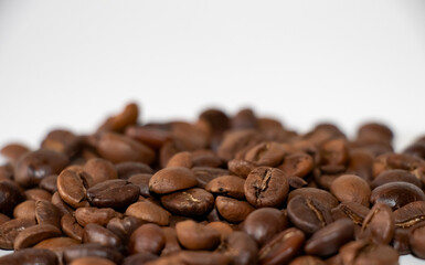 Coffee beans scattered. Aromatic brown coffee beans scattered on surface isolated on white background. Space for text. Selective Focus.
